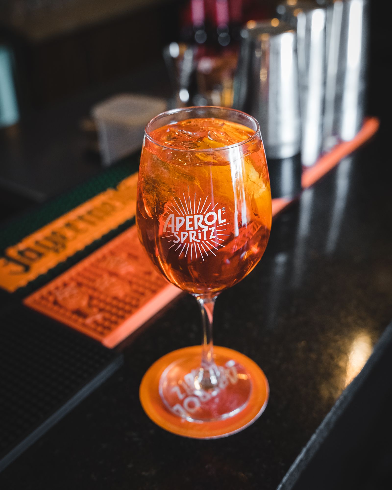 Un verre de spritz orangé sur un comptoir de bar