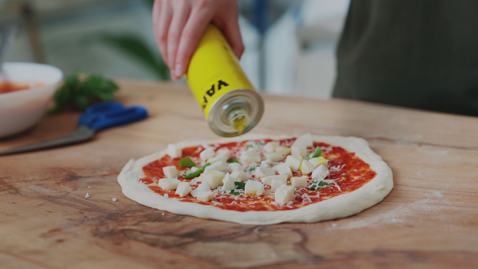 Un filet d’huile d’olive sur une pâte garnie de tomate et de fromage